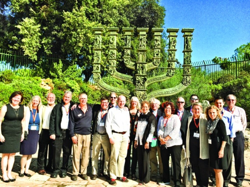 The group take a moment for a photo in front of the Benno Elkan Knesset Menorah located on the edge  of the Rose Garden. It was created in 1956 by Benno Elkan and is 5 meters high. /Marty Cooper